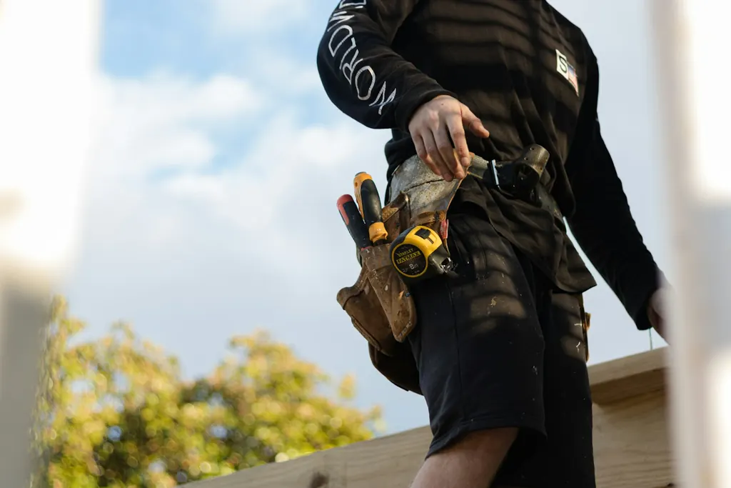 A carpenter's tool belt with a tape measure and hammer, photographed at waist height